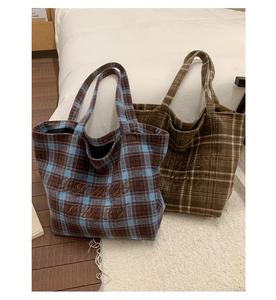 Detail of plaid embroidered tote bags in blue and brown woolen fabric with wide straps