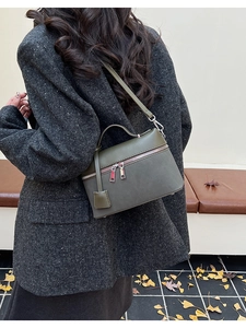 Olive green tote bag with metal charm shown as a crossbody on a grey tweed coat