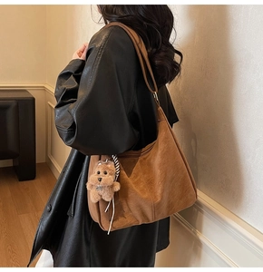 Dettaglio di una borsa hobo in pelle marrone con un simpatico ciondolo a forma di cane in peluche