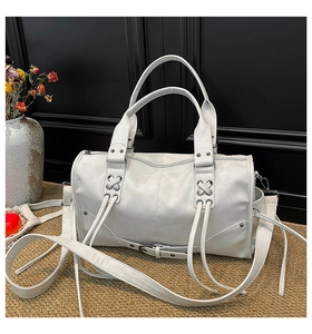 Detail of white boston bag featuring metal rivets, leather laces and silver hardware