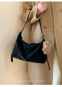 Détail du sac hobo en daim noir avec coutures fines, zip doré et breloque ours en peluche