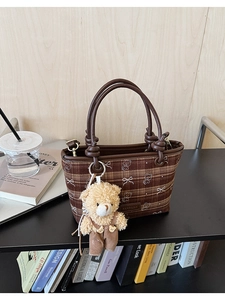 Detail of checkered canvas bucket bag with leather handles and cute bear charm