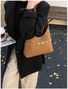 Brown vintage suede tote bag styled with black coat and autumn fallen leaves