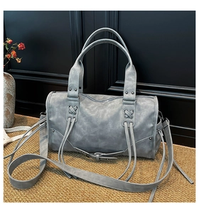 Detailed view of the dark gray distressed leather texture and crisscross lacing on bag