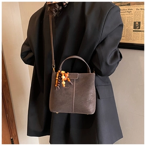 Detail of dark grey retro bucket bag with vintage wooden bead charm and matte texture