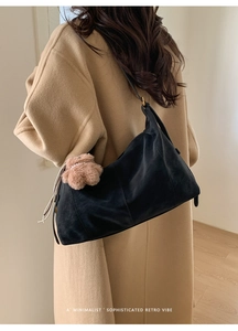 Détail du sac bandoulière vintage en daim noir avec breloque ours sur manteau laine