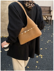 Detail of tan suede shoulder bag featuring contrast white stitching and gold buckle hardware