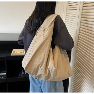 Detail of beige large capacity tote bag featuring natural pleated texture and zipper closure