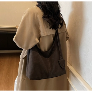 Macro shot of dark brown minimalist hobo bag featuring soft matte texture and leather charms