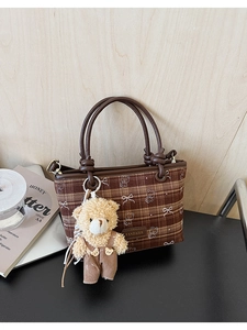 Detail view of brown plaid bucket bag featuring bear patterns and a plush bear charm