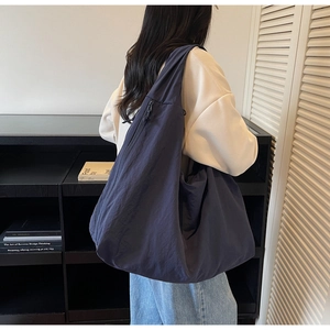 Detailed view showing the drape and large capacity of the nylon tote bag on shoulder