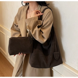 Detail of dark brown suede hobo tote with matching pouch shown on woman in trench coat