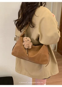 Détail d'un sac cabas vintage en cuir avec un charmant ours en peluche sur la bandoulière