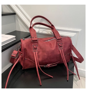 Detail shot of vintage burgundy leather tote with fringe tassels on dark stairs
