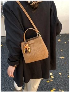 Close-up of vintage brown bucket bag with decorative beads and autumn leaves background