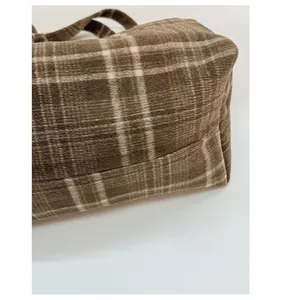 Detail shot of the widened bottom structure on this brown plaid embroidered tote bag