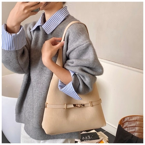 Detail of a large beige suede tote bag with elegant gold buckle and shoulder strap