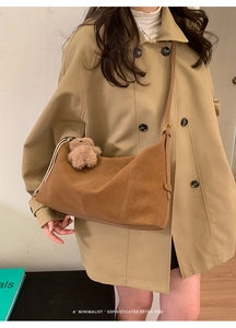 Détail du sac fourre-tout en daim marron avec surpiqûres et breloque ours en peluche