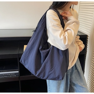 Large navy nylon hobo bag shown on shoulder, highlighting spacious casual slouchy design