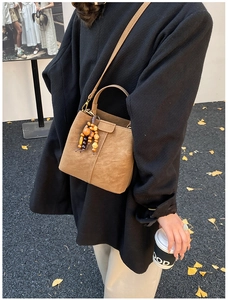 Sac seau marron avec breloque en bois présenté dans un cliché de mode de rue authentique