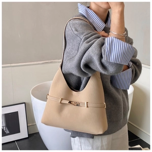 Close-up of beige suede shoulder bag with elegant metallic buckle on a mannequin