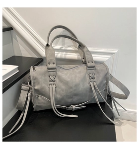 Detail of grey vintage leather tote bag with distressed finish and tassel decorations