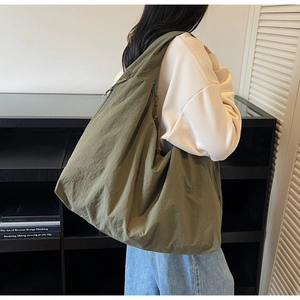 Detailed side view of an olive green large nylon tote bag with drawstring texture details