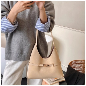 Detail of cream hobo bag showing gold twist-lock buckle and long shoulder strap