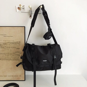 Detail of black messenger bag with wide strap and detachable round mini pouch