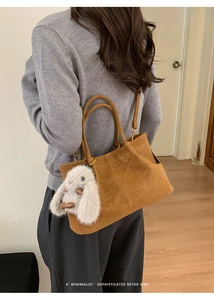 Gros plan d'un sac cabas en daim marron avec un charme de lapin blanc en peluche chic