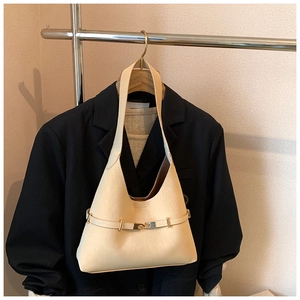 Detailed shot of a beige crescent underarm bag with gold buckle on a black blazer