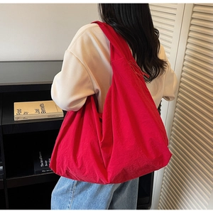 Close-up of a large red hobo bag showing soft canvas texture and minimalist drape design