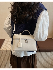Detailed back view of a beige pebbled leather shoulder bag worn by a model in a casual outfit