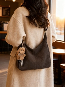 Borsa hobo retrò in pelle scamosciata marrone scuro con ciondolo a cucciolo in un caffè