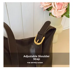 Detail of dark brown leather bucket bag with adjustable strap and gold metal buckle