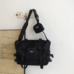Detail of black nylon messenger bag featuring a white logo and removable mini zip pouch