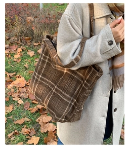 Detail of vintage brown plaid tote bag with embroidery on autumn grass background