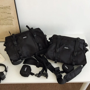 Detail of black nylon messenger bag with functional straps and detachable small pouch