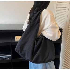 Detail view of large black nylon tote bag showing its wrinkled texture and slouchy shape