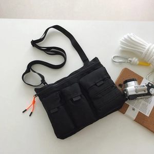 Détail de la sacoche tactique en nylon noir avec trois poches et tirettes orange vif