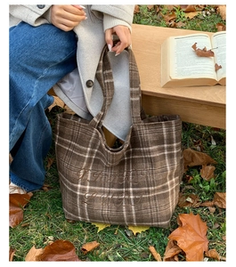 Detail of vintage brown plaid tote bag with elegant floral embroidery in autumn setting