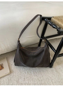 Détail d'un grand sac hobo rétro marron foncé au fini mat sur un tapis blanc texturé