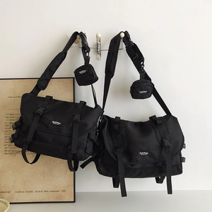 Detail view of black utility messenger bags with round coin purses and buckle closure