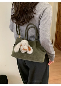 Deep green suede bucket bag featuring a cute white rabbit plush charm and dual straps