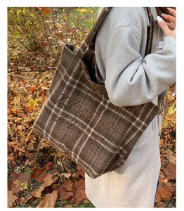 Detail of vintage brown plaid tote bag with embroidery shown in an autumn park