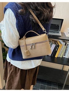Close-up of khaki pebbled leather handbag with adjustable strap in a modern studio setting