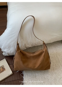 Détail de sac hobo en daim marron avec coutures précises et boucles métalliques dorées
