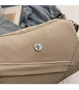 Detailed macro view of silver butterfly logo hardware on textured beige shoulder bag