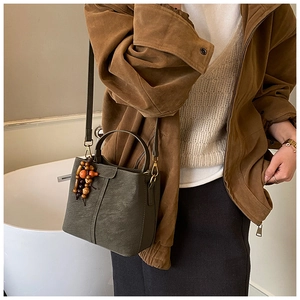Detail view of a vintage olive green bucket bag with leather texture and bead charm