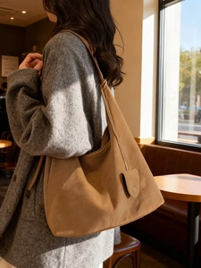 Large brown suede tote bag for women shown in a cafe setting with soft natural light